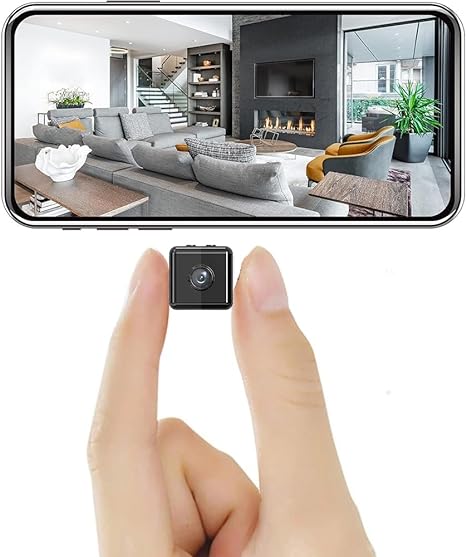 Het kleine zwarte vierkante cameraatje tussen duim en wijsvinger, met erboven een smartphone die een live beeld van een woonkamer toont. 1