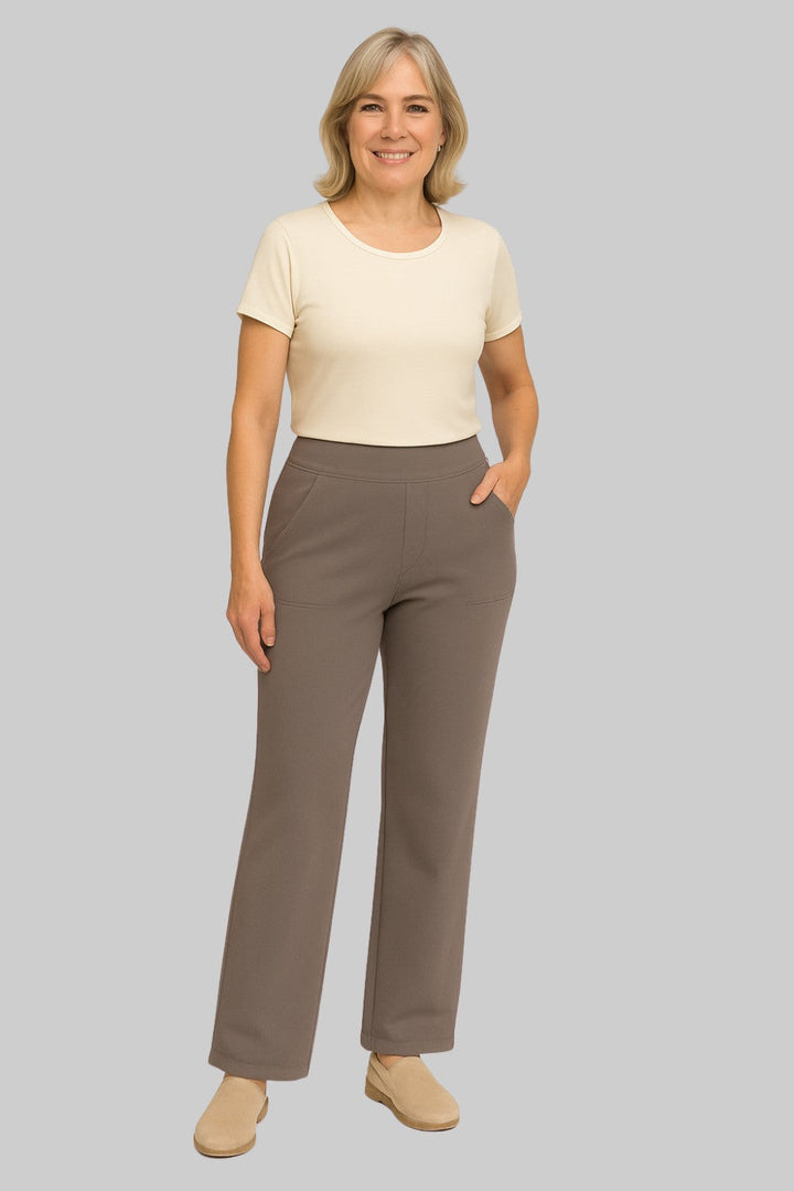 Lachende vrouw in taupebruine broek met opgestikte zakken, gecombineerd met een crèmekleurig T-shirt en beige instappers. 2