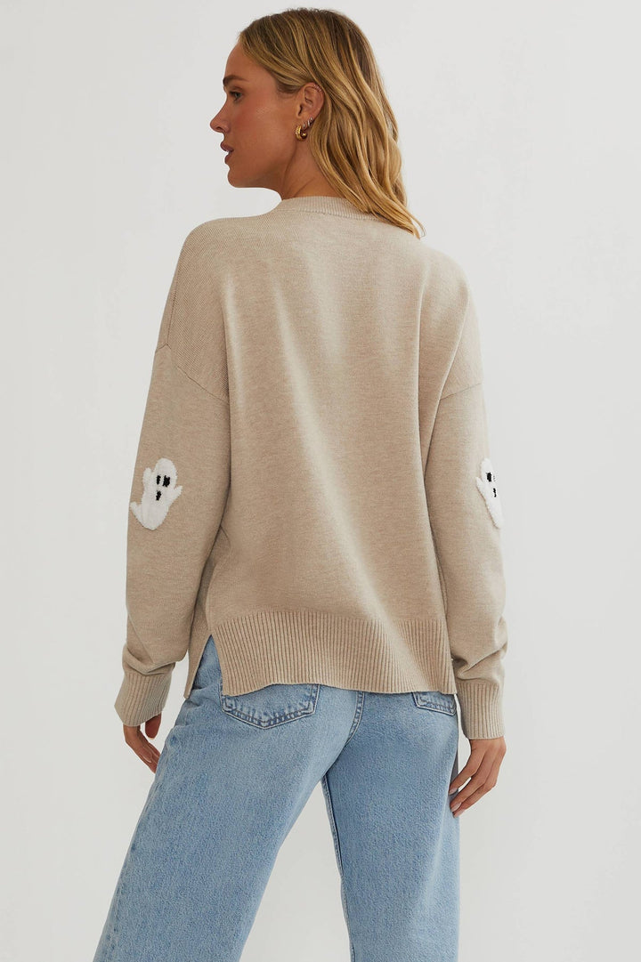 Achterkant van de beige trui op een model, effen rug met een spookje op elke mouw en splitjes in de gerib de zoom. 5
