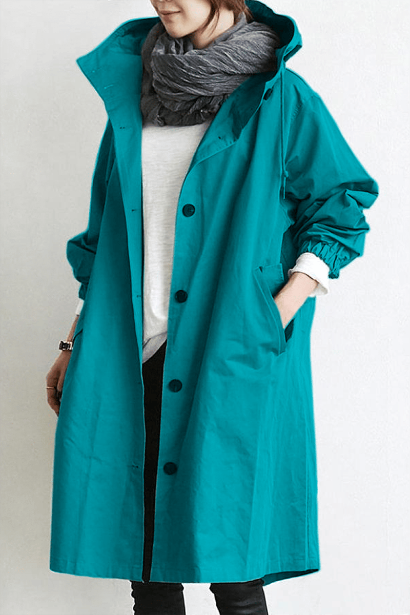 Turquoise lange regenjas met capuchon en knopen, gedragen met witte trui en grijze sjaal 7
