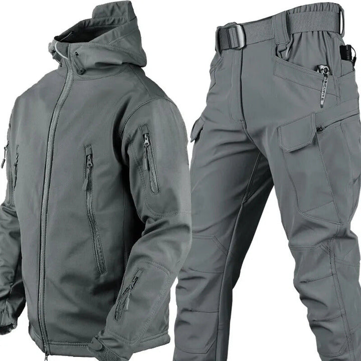 Grijze jas met capuchon en bijpassende cargobroek met riem, samen als set getoond op een witte achtergrond. 10